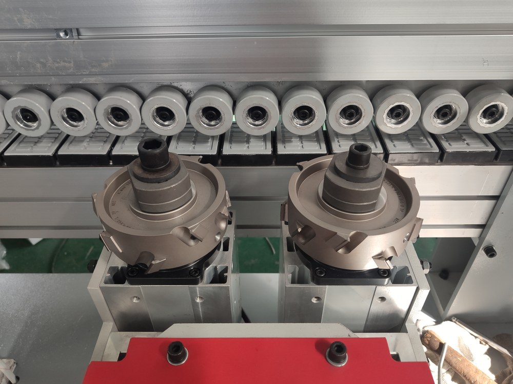 Two motorised trimming cutter heads inside an automatic edge banding machine
