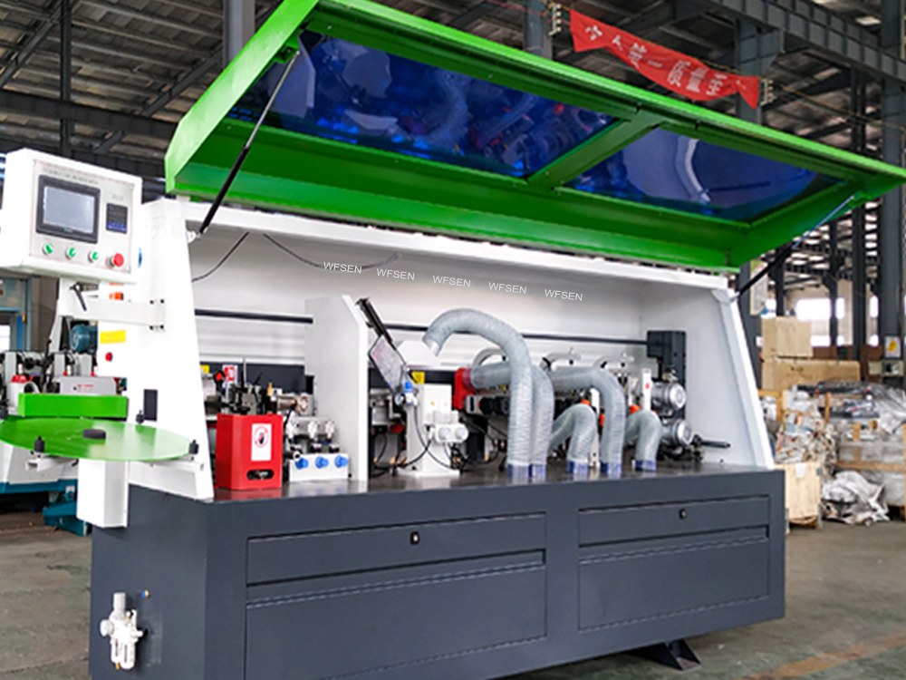 Inside a full automatic edge banding machine with the hood open, showing the station chain along the bed